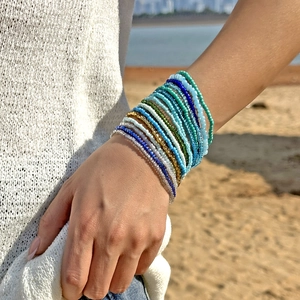 Kleurrijke gelaagde damesarmbandset met kralen in boho-stijl op een zonnig zandstrand