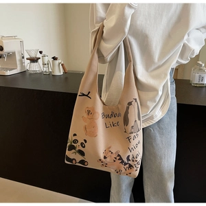 Close-up of beige canvas tote bag with colorful cartoon animal illustrations and shoulder strap