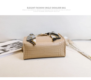 Détail d'un sac à main beige à motif crocodile avec un foulard en soie décoratif sur l'anse