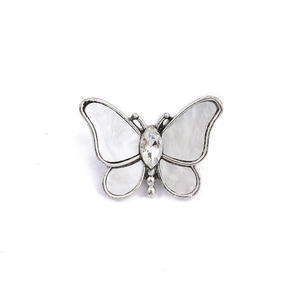 Detail view of butterfly brooch with white shell wings and sparkling crystal center