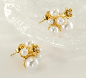 Detailed macro shot of gold flower earrings with clustered pearls and zircon center