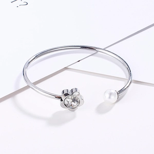 Detail of silver titanium bangle featuring flower zircon and a white pearl accent