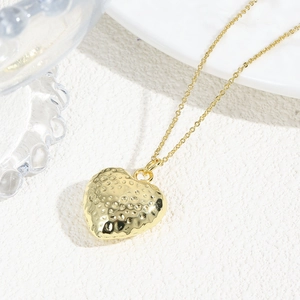 Close-up of a 18k gold plated hollow heart necklace with textured hammered finish