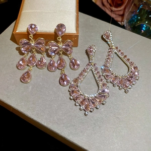 Détail de boucles d'oreilles nœud rose et goutte d'eau avec des accents de diamant
