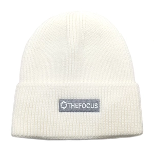 Detailed texture of off-white ribbed knit beanie with THEFOCUS woven label patch