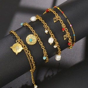 Vintage gold layered bracelets with evil eye, pearls and sun charms on dark display
