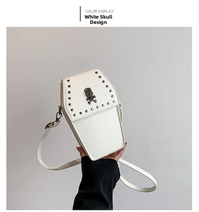 Detail shot of white coffin-shaped crossbody bag with silver skull and metal rivets