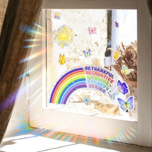 Detailed view of rainbow window stickers with butterflies and inspirational text in sunlight