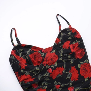 Dettaglio dell'abito floreale con rose rosse su tessuto mesh nero e balze con pieghe