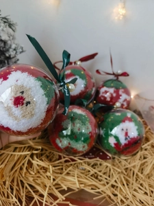 Close-up of festive Christmas ball gift box with red Santa and green tree coral fleece socks