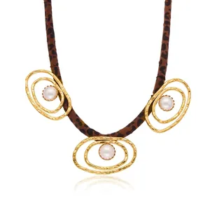 Detail view of leopard print silk scarf necklace with gold rings and white pearls