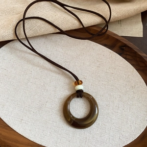 Vue détaillée d'un pendentif en acrylique avec perles rétro et cordon brun foncé
