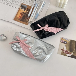 Glossy black and silver bow pencil cases displayed on a desktop with modern accessories