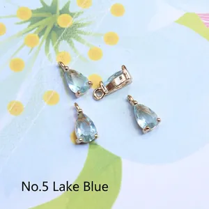 Detail view of water drop-shaped lake blue glass charms with gold-plated metal edges
