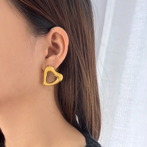 Close-up of a model wearing minimalist 18K gold plated hollow heart-shaped stud earrings