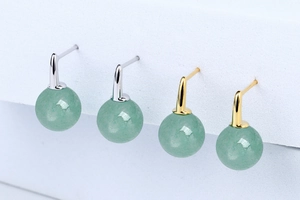 Macro shot of gold and silver S925 sterling silver earrings with round green aventurine beads