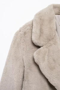 Detailed close-up of soft beige faux fur texture on collar and shoulder of the warm winter coat