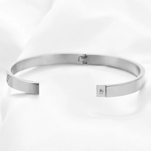 Sleek 6mm silver stainless steel hinged bangle displayed on soft white satin fabric