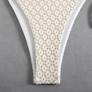 Close-up of white crochet lace details and high-cut edges on the bikini bottom