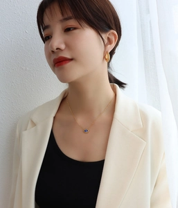 Détail du collier mauvais œil doré avec pendentif bleu et petit diamant étincelant