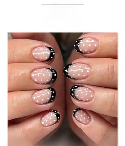 Close-up of black French tips with white polka dots on nude oval press-on nails