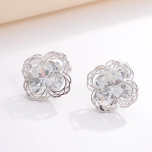 Macro shot of silver geometric flower earrings with sparkling zircon stones on a white surface