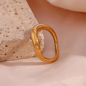 Macro shot of gold-plated irregular wavy ring on textured stone and pink silk background