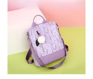 Detail of purple floral Oxford backpack with plush ball charm on a colorful background