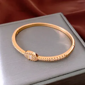 18K gold plated oval clasp bangle with micro-pave crystals on red silk luxury box