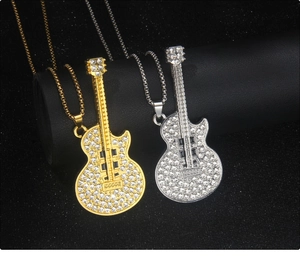 Detail view of silver and gold guitar pendants with sparkling rhinestones on black background