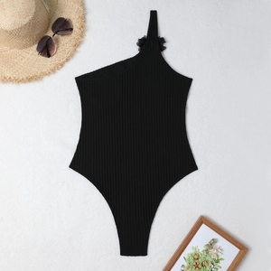 Detail of one-shoulder black ribbed swimsuit featuring a 3D floral accent on the strap