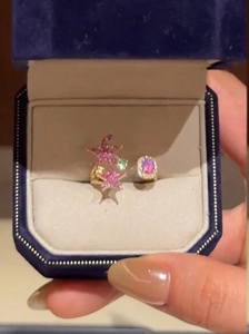 Close-up of golden star-shaped ring with pink enamel and oval gem in a velvet box