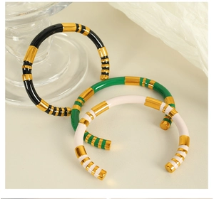 Detailed close-up of vintage gold bangle set with black, green, and cream enamel stripes