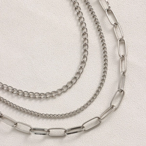 Detailed view of three silver metal layered waist chains with hollow heart pendants