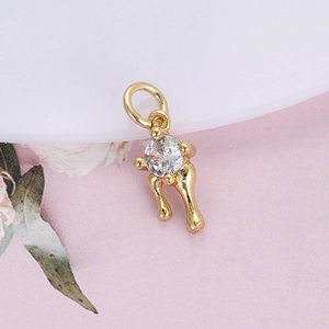 Detailed view of a gold-plated charm pendant featuring a clear gemstone and artistic leg shape
