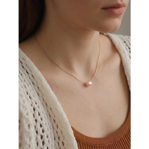 Elegant gold chain necklace with a single white baroque freshwater pearl on female model