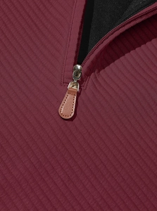 Detail of burgundy ribbed fabric with silver metal zipper and brown leather puller tab
