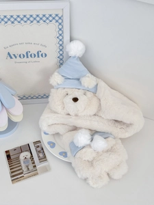 Close-up of soft plush bear scarf with blue nightcap and white fluffy pom-poms