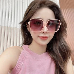 Detail of square pink frame sunglasses with purple gradient lenses worn by a model