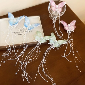 Detail of elegant butterfly hair clips with pearl beads and hanging colorful silk tassels