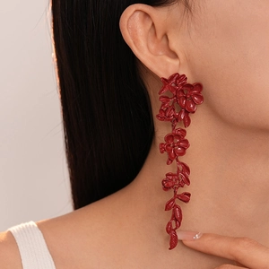 Close-up of deep red floral dangle earrings with a glossy finish on a model's ear