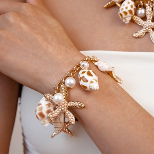 Close-up of golden starfish and shell charms with pearls on a double-layer bracelet