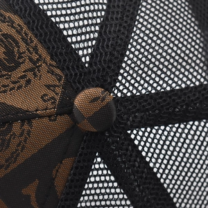 Close-up of mesh trucker cap crown featuring letter print fabric and top button detail