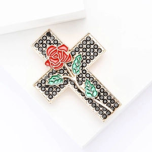 Vintage gold cross brooch with black rhinestones, red rose and green leaves on white background