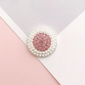 Macro view of round silver charm with pink rhinestones and white pearls for DIY crafts