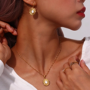 Golden sunburst pendant necklace with matching earrings and rings worn by a model
