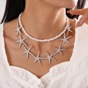 Close-up of a layered necklace set with white pearls and silver starfish pendants