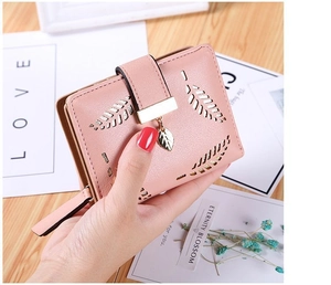 Pink women's wallet with laser-cut leaf pattern and a gold leaf metal pendant detail