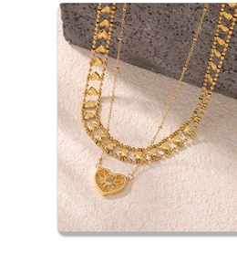 Detail of layered gold heart necklace with hollow pendant and central zircon inlay