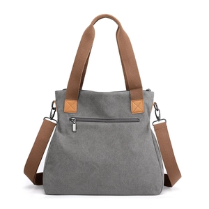 Minimalist grey canvas handbag with brown woven handles and detachable shoulder strap